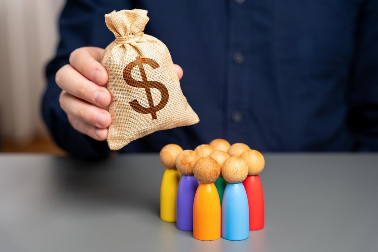 Homem segurando uma bolsa com figuras de madeira de pessoas.